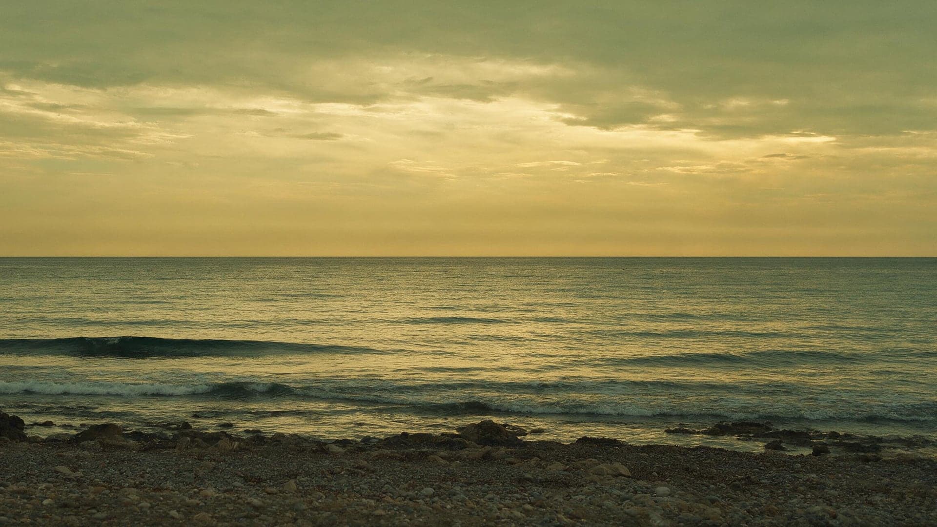 Mer Méditerranée calme au crépuscule, rivage rocheux vide, ciel or et sauge