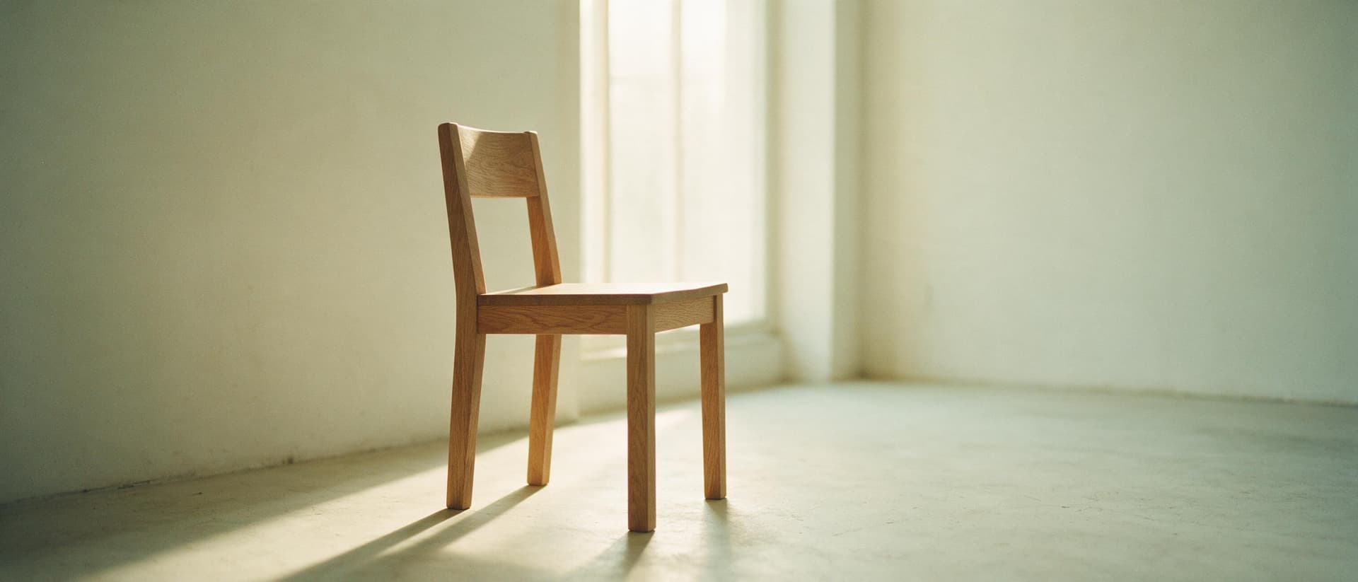 Chaise en chêne tournée vers une haute fenêtre baignée de lumière du matin