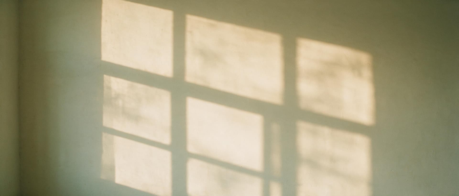 Lumière de fin de journée et ombre douce d'une fenêtre sur un mur d'enduit clair